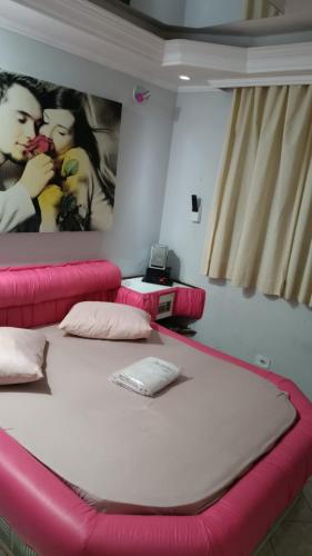 a bed in a room with pink pillows and a wall with posters at Hotel Obsession in Pôrto Esperidião