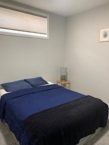 a bedroom with a blue bed and a window at Karis Home in Airdrie