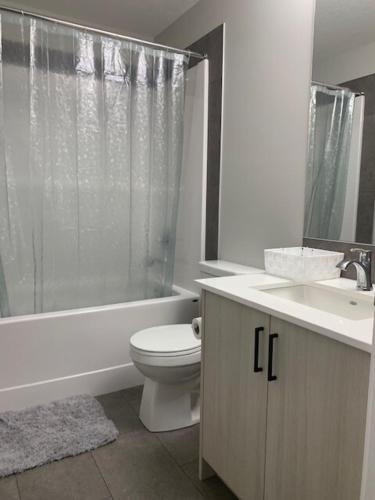 a bathroom with a toilet and a sink and a shower at Karis Home in Airdrie
