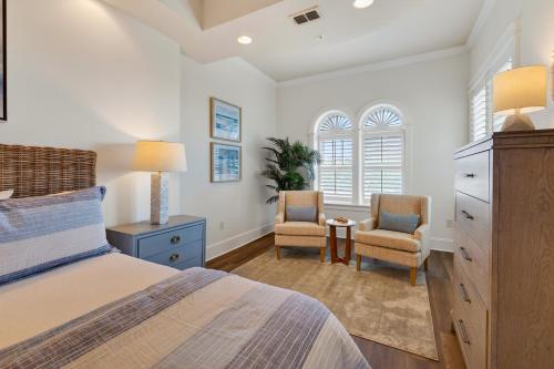 a bedroom with a bed and two chairs and a dresser at Sea Gate 303 in Saint Simons Island