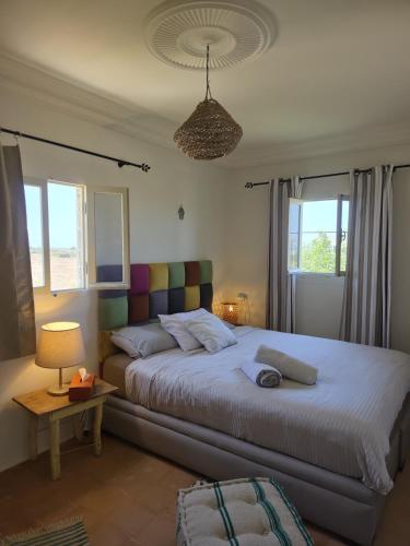 a bedroom with a large bed and two windows at Beach House with Sea Views and Rooftop Terrace in Sidi Kaouki
