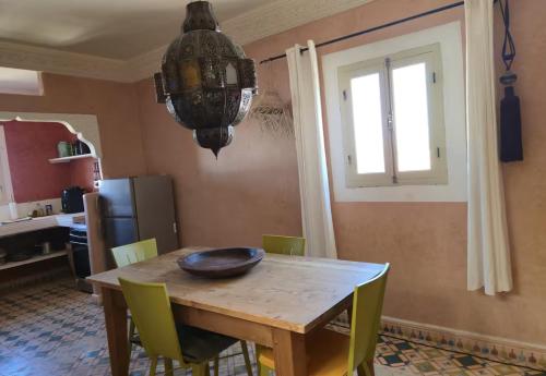 a dining room table with green chairs and a chandelier at Beach House with Sea Views and Rooftop Terrace in Sidi Kaouki