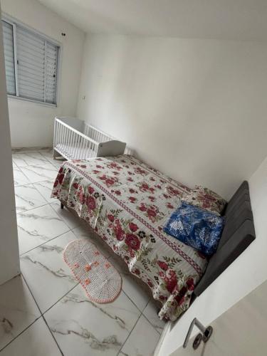 a bedroom with a bed with a blanket and a crib at Lazer Oceanos in São Vicente