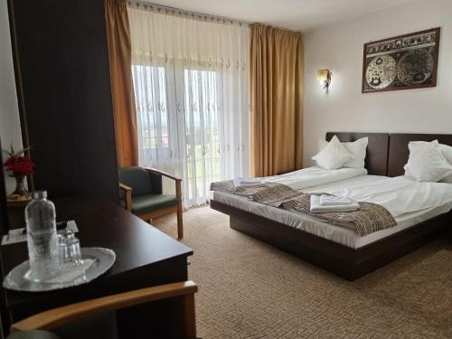 a hotel room with a bed and a table and a desk at Pensiunea Emma in Sâmbăta de Sus