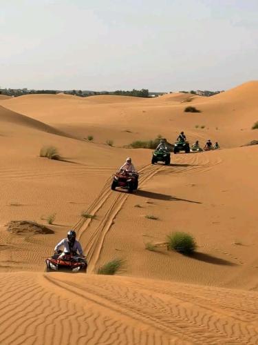 a group of people riding on quad bikes in the desert at Bivouac Camel Trips in Merzouga