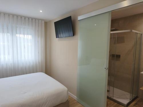 a bedroom with a bed and a glass shower at Pensión Vázquez in Vimianzo