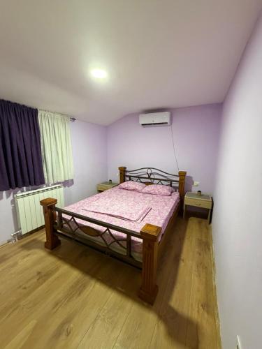a bedroom with a bed in a room with purple walls at Apartman M&S in Golubovci