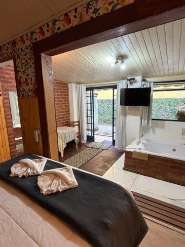 a bedroom with a large bed and a tub at Pousada A Casa da Fazenda in Santo Antônio do Pinhal
