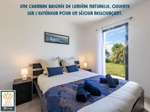 a bedroom with a large bed with a large window at Les Alizés in Plouhinec