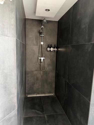 a bathroom with a shower with black tiles at Apartment Landglück Overath in Overath