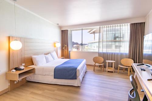 a hotel room with a bed and a large window at Wyndham Concepcion Pettra in Concepción