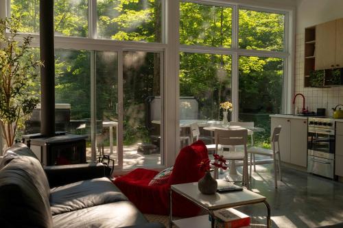 a living room with a couch and a kitchen with large windows at The Lofti in Sainte Béatrix