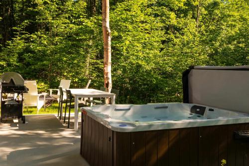 a jacuzzi tub on a patio with a table at The Lofti in Sainte Béatrix