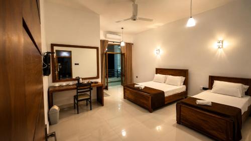 a bedroom with two beds and a desk and a mirror at Araliya Hotel in Badulla