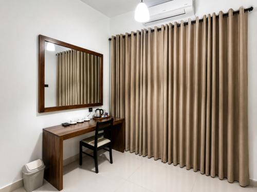 a bathroom with a desk with a mirror and a shower curtain at Araliya Hotel in Badulla