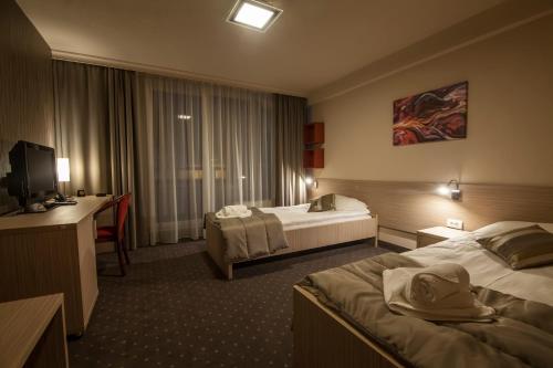 a hotel room with two beds and a desk at Drina Hotel in Bijeljina