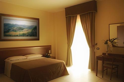 a bedroom with a bed and a desk and a window at Hotel Ruffirio in Vinchiaturo