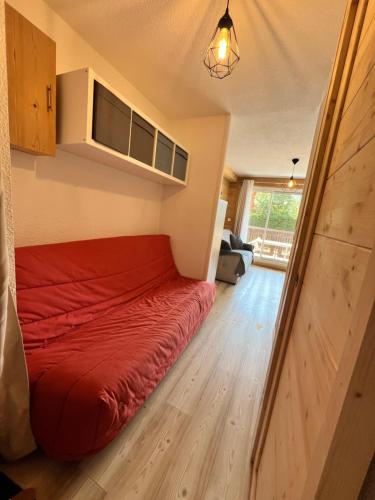 a bedroom with a red bed in a small room at Chaleureux appartement moderne in Briançon
