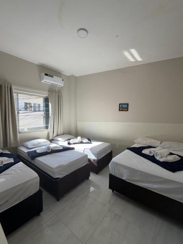a bedroom with three beds in a room at Hotel Pousada Romanos in Aparecida