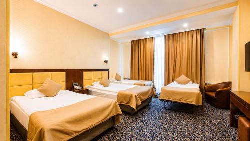 a hotel room with two beds and a chair at Ruma Qala Hotel in Sheki
