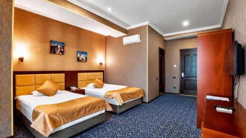 a hotel room with two beds and a television at Ruma Qala Hotel in Sheki