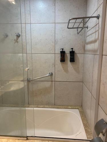 a shower with a glass door and a tub at Flat Fabuloso Hotel Berrini in São Paulo