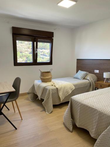 a bedroom with two beds and a table and a window at Casas de Vacaciones Ibaiale in Cazadores