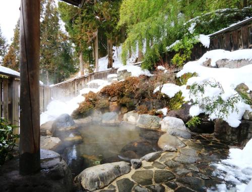a pond with snow on the ground next to a fence at Miyamaso in Takayama