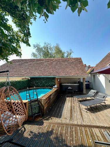 a wooden deck with a swimming pool and a house at La Longère du Menuisier : Spa-Châteaux-Beauval in Romorantin