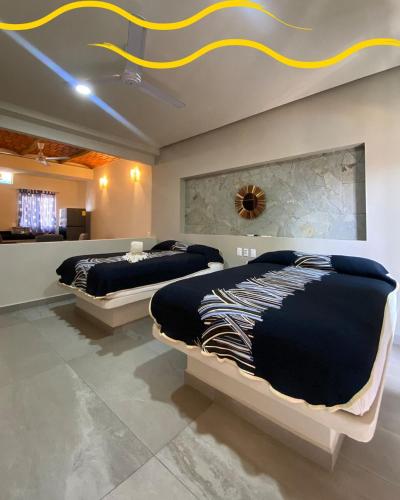 two beds in a bedroom with a ceiling at Villas & Suites Santa Monica in Rincon de Guayabitos