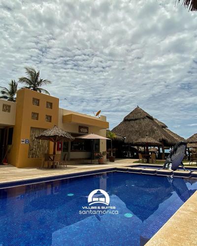 a swimming pool in front of a resort with a building at Villas & Suites Santa Monica in Rincon de Guayabitos