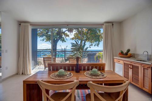 a kitchen with a table with chairs and a large window at Cairé Suites in Itacaré