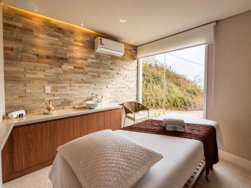 a bedroom with a bed and a sink and a window at Castelos do Vale by Livá OFICIAL in Bento Gonçalves