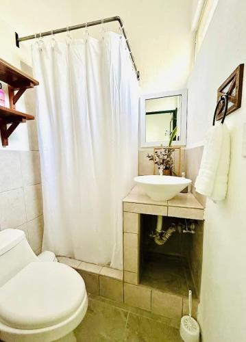 a bathroom with a white toilet and a sink at Lu House in Flores