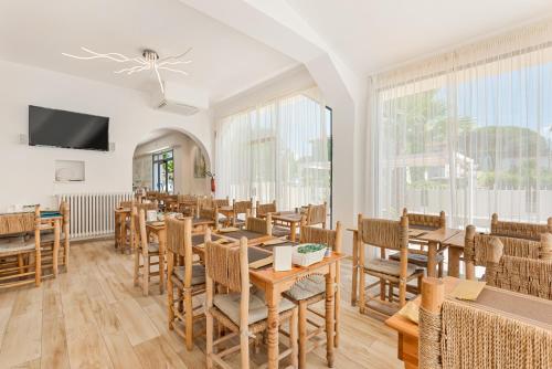 a restaurant with wooden tables and chairs and windows at Hotel La Perla in Marina di Massa