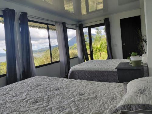 a bedroom with two beds and large windows at Villa Terraza in El Castillo de La Fortuna