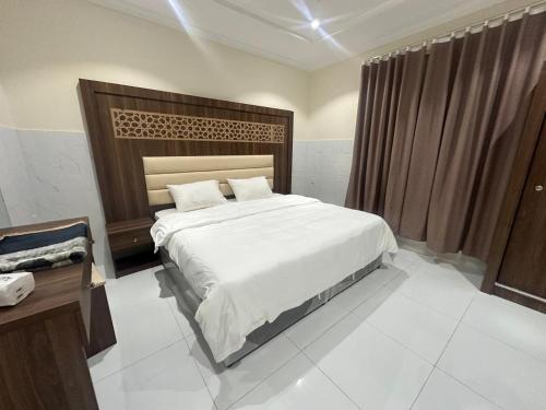 a bedroom with a large bed with a wooden headboard at كيان التيسير - حي التيسير in Jeddah