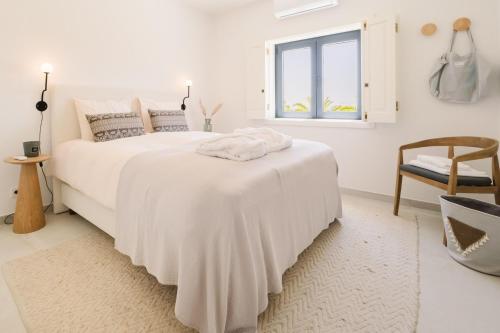 a white bedroom with a large bed and a window at Vila das Acácias - Boutique Villa in Wine Country in Alenquer