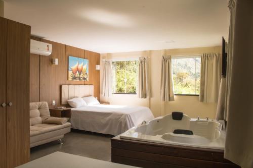 a hotel room with a bed and a bath tub at Vale Das Araras Nas Videiras in Araras Petropolis