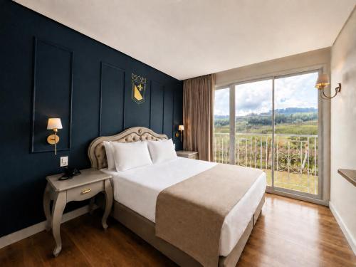 a bedroom with a large bed and a large window at Castelos do Vale by Livá OFICIAL in Bento Gonçalves