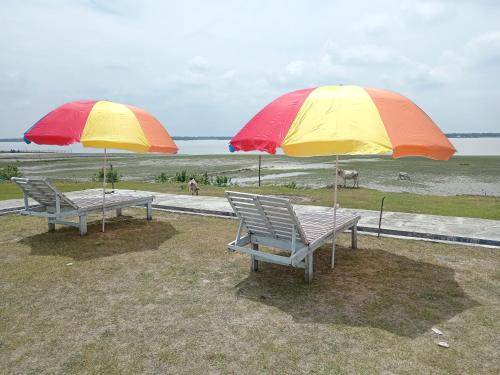 two chairs and two umbrellas on the beach at Bonolota Eco Villa in Mongla