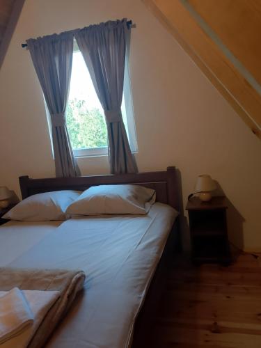 a bedroom with a bed and a window with blue curtains at House Vasilije in Žabljak