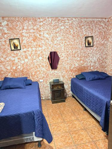 a bedroom with two beds and a table and a wall at Cristales de Antigua La Calzada in Antigua Guatemala