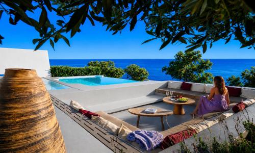 a woman sitting on a couch overlooking the ocean at Santorini Heights in Pyrgos