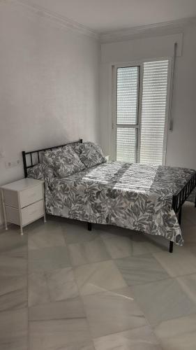 a bedroom with a bed and a dresser and a window at Apartamentos Lebrero in San Fernando
