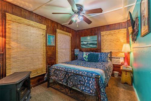 a bedroom with a bed and a ceiling fan at Come Friday Cottages in Bacliff