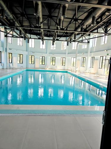 a large swimming pool with blue water in a building at Welcome3 in Achʼqva