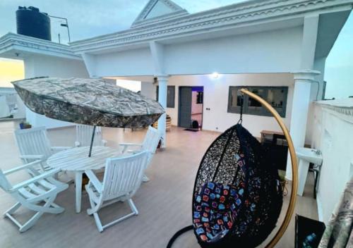 eine Veranda mit Schaukel und Sonnenschirm in der Unterkunft Hôtel 550 in Cotonou Cadjehoun
