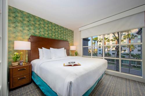 a hotel room with a bed and a large window at Peacock Suites in Anaheim