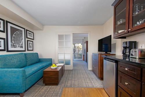 a living room with a blue couch and a kitchen at Peacock Suites in Anaheim